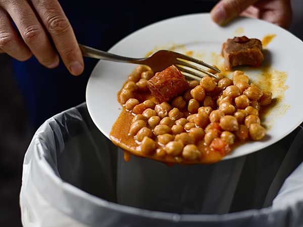 Person scraping leftovers into trashcan.