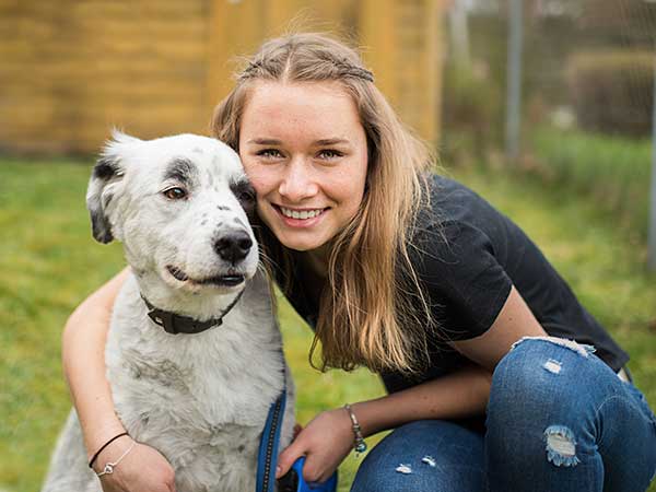 Young woman hugging Australian Shepherd.