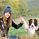Lady giving high-five to her Australian Shepherd.